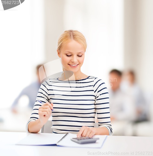 Image of woman with notebook and calculator studying