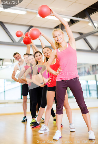 Image of group of smiling people working out with ball