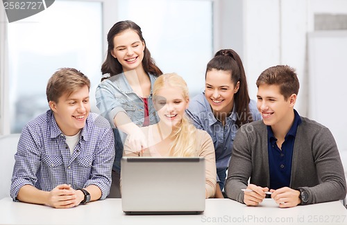 Image of smiling students looking at laptop at school