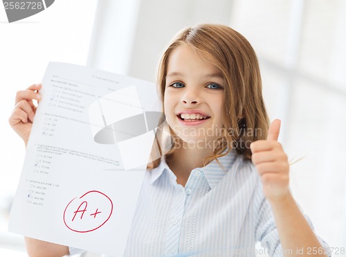 Image of smiling little student girl with test and A grade