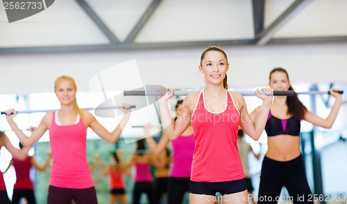 Image of group of smiling people working out with barbells