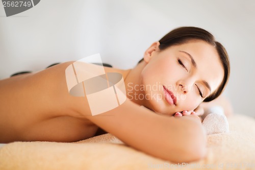 Image of beautiful woman in spa salon with hot stones