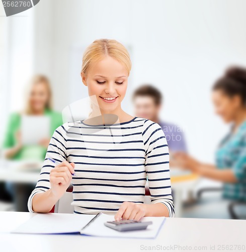 Image of woman with notebook and calculator studying