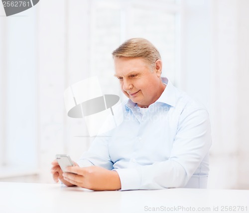 Image of old man at home with smartphone