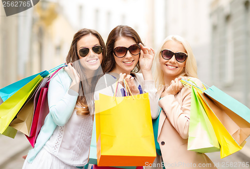 Image of three smiling girls with shopping bags in ctiy