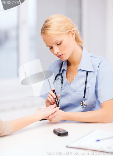 Image of female doctor or nurse measuring blood sugar value