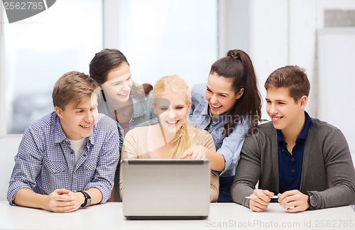 Image of smiling students looking at laptop at school