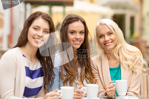 Image of three beautiful girls drinking coffee in cafe