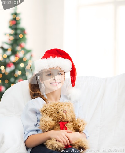 Image of smiling girl in santa helper hat with teddy bear