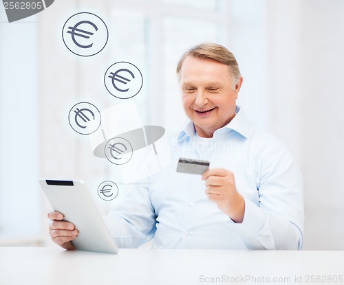 Image of old man with tablet pc and credit card at home