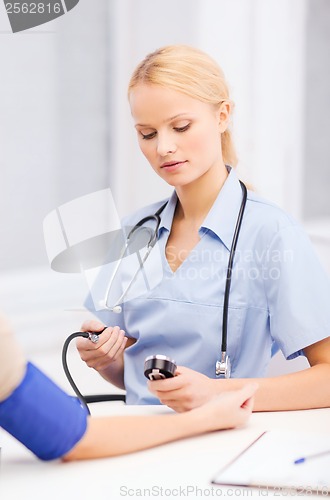 Image of female doctor or nurse measuring blood pressure