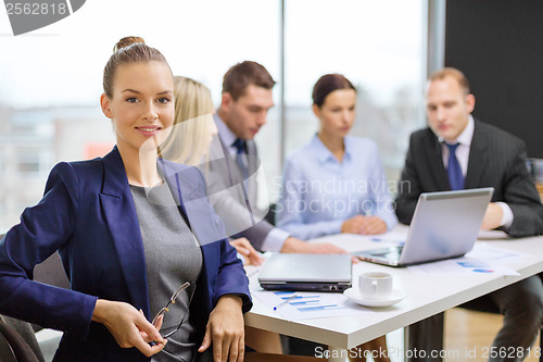 Image of businesswoman with glasses with team on the back