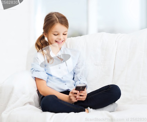 Image of smiling girl with smartphone at home