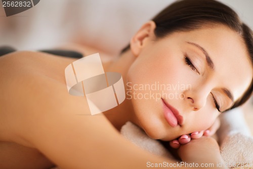 Image of beautiful woman in spa salon with hot stones