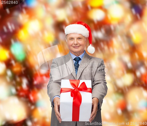 Image of smiling man in suit and santa helper hat with gift