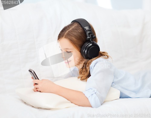 Image of girl with smartphone and headphones at home