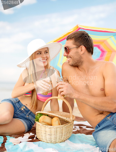 Image of smiling couple having picnic on the beach