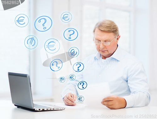 Image of old man in eyeglasses filling a form at home