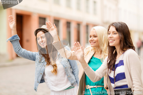 Image of three beautiful girls waving hands