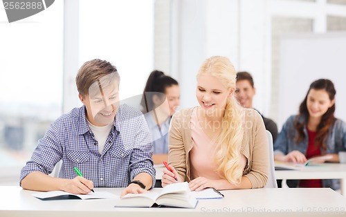 Image of two teenagers with notebooks and book at school