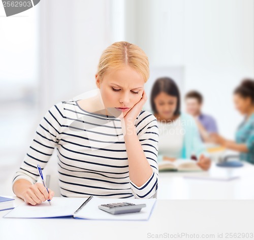 Image of woman with notebook and calculator studying