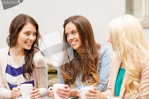 Image of three beautiful girls drinking coffee in cafe