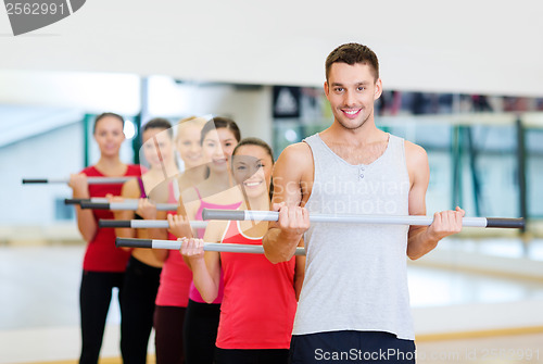 Image of group of smiling people working out with barbells