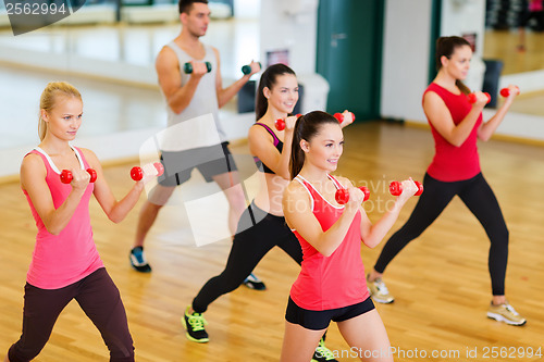 Image of group of smiling people working out with dumbbells