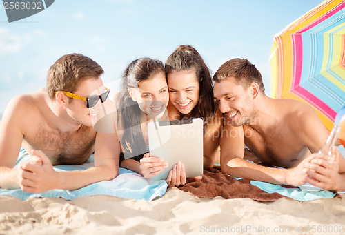 Image of group of smiling people with tablet pc on beach