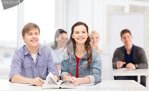 Image of two teenagers with notebooks and book at school