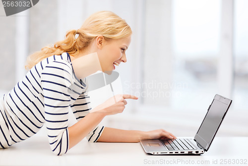 Image of smiling student girl pointing her finger at laptop