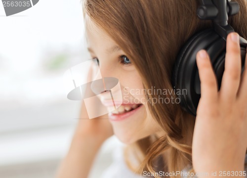 Image of smiling little girl with headphones at home