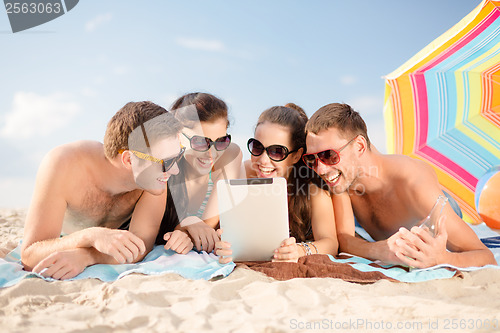 Image of group of smiling people with tablet pc on beach