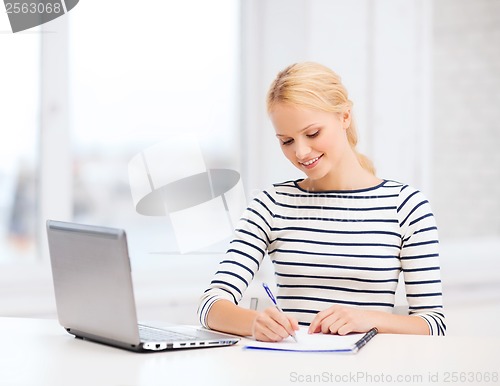 Image of smiling student with laptop computer and documents
