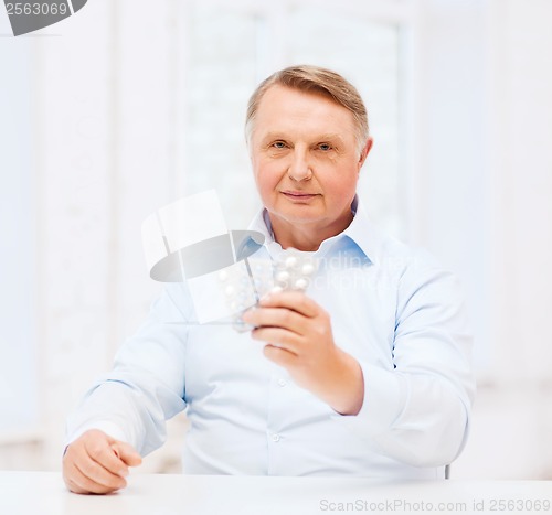 Image of old man with pack of pills