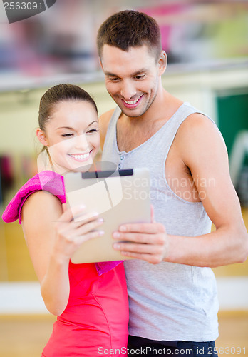 Image of two smiling people with tablet pc in the gym