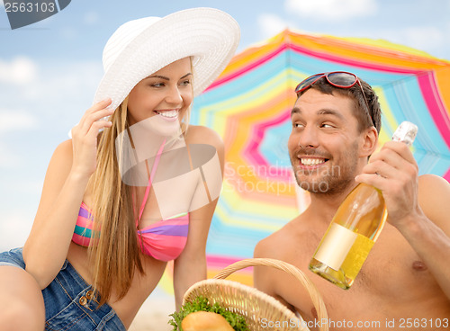 Image of smiling couple having picnic on the beach