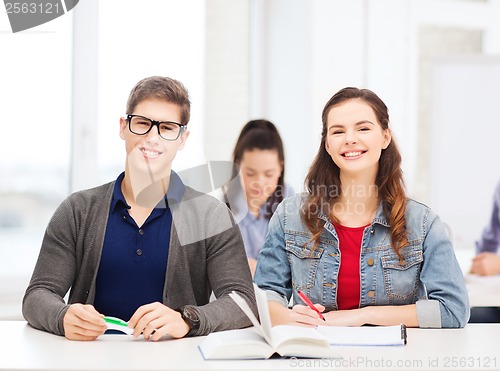 Image of two teenagers with notebooks and book at school