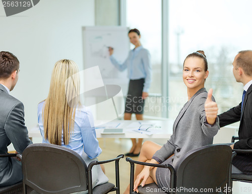 Image of businesswoman with team showing thumbs up