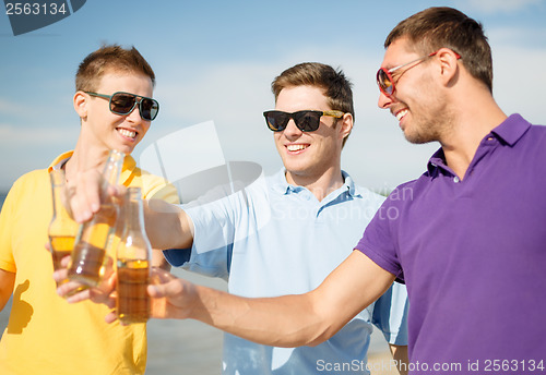 Image of group of male friends having fun on the beach