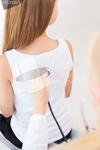 Image of doctor with stethoscope listening to child back