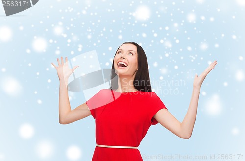 Image of smiling young woman in red dress with hands up