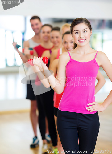 Image of group of smiling people with dumbbells in the gym