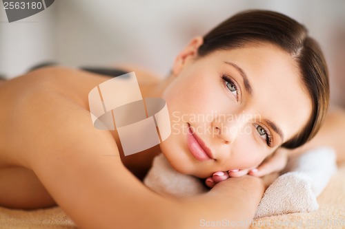 Image of beautiful woman in spa salon with hot stones