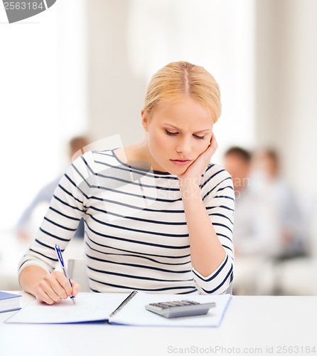 Image of woman with notebook and calculator studying