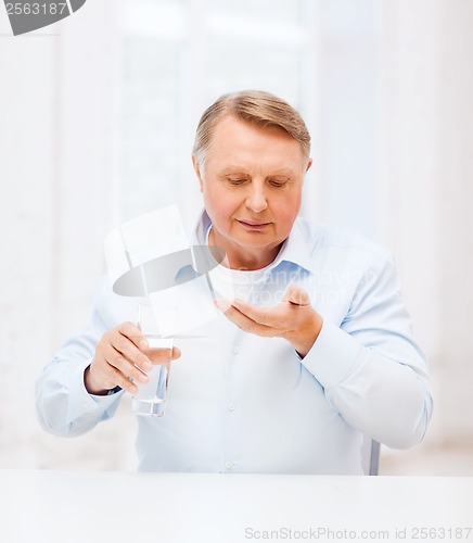 Image of old man with pills ang glass of water