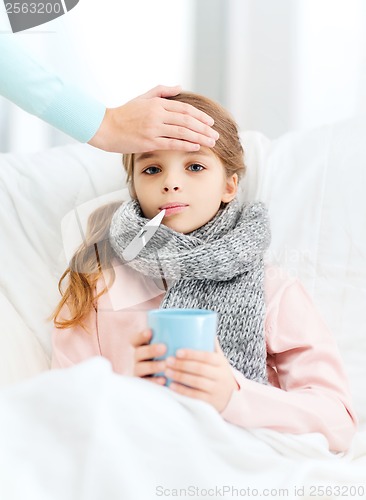 Image of ill girl child with thermometer and caring mother