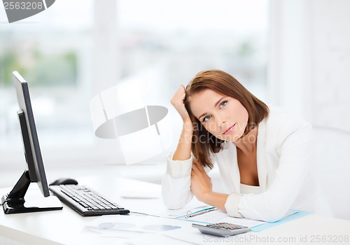 Image of woman with computer, papers and calculator