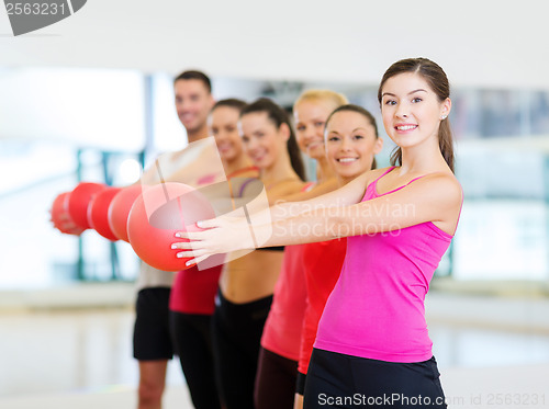 Image of group of smiling people working out with ball