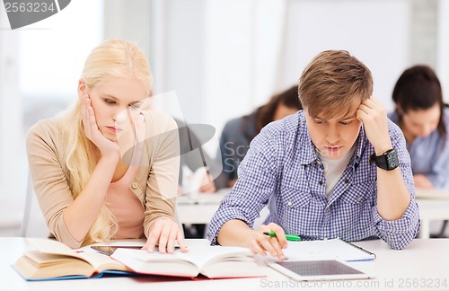 Image of tired students with tablet pc, notebooks and books